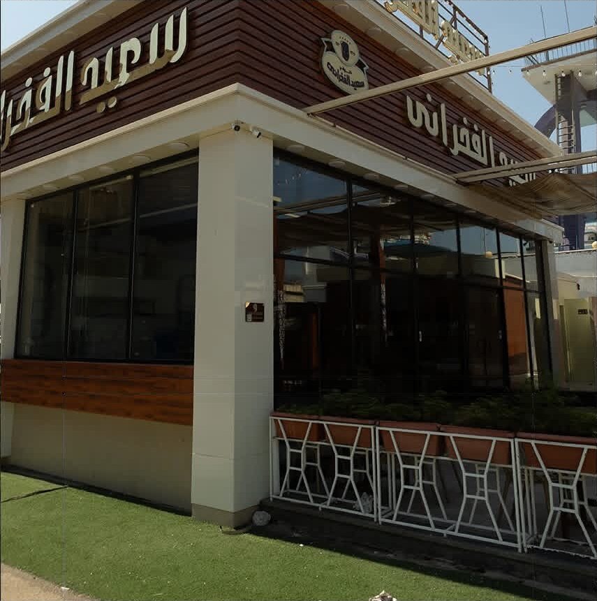 Timber‑clad façade with Arabic signage by day